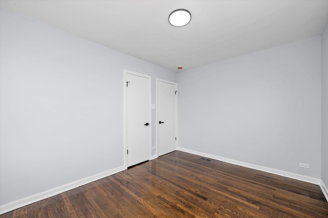 spare room featuring baseboards and dark wood-style floors