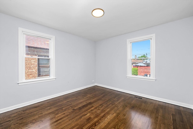 unfurnished room featuring baseboards and dark wood-style floors