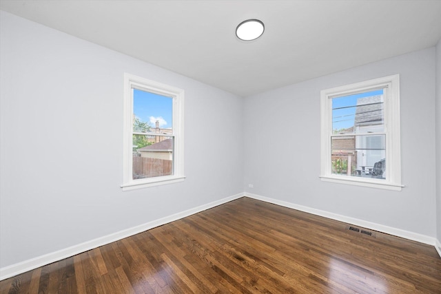 unfurnished room featuring baseboards, plenty of natural light, and dark wood-style floors