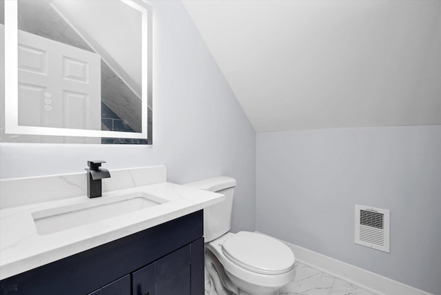 bathroom featuring marble finish flooring, toilet, vanity, lofted ceiling, and baseboards