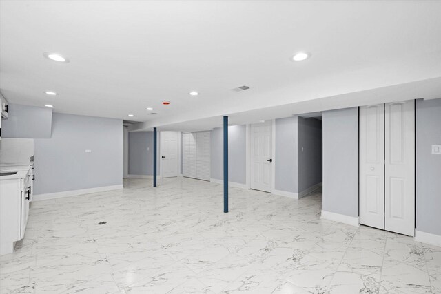 finished basement with recessed lighting, baseboards, and light marble finish floors