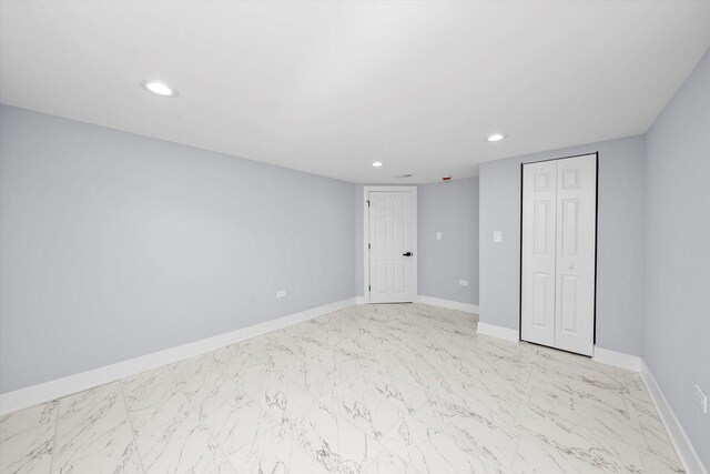 unfurnished bedroom with marble finish floors, recessed lighting, baseboards, and a closet