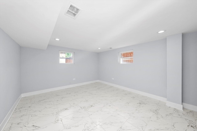 unfurnished room with healthy amount of natural light, recessed lighting, baseboards, and light marble finish floors