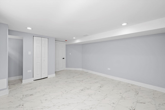 finished below grade area with recessed lighting, baseboards, and light marble finish flooring