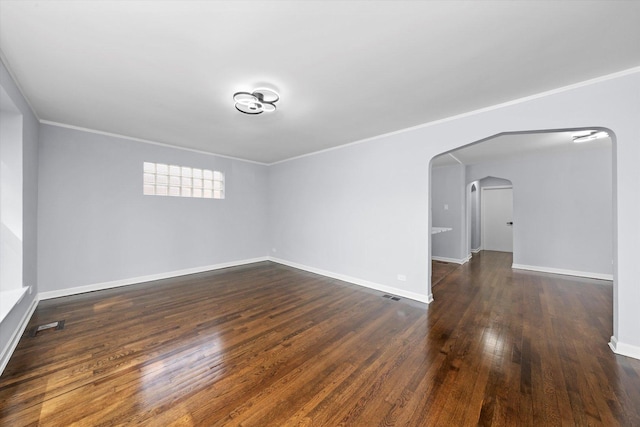 unfurnished room featuring arched walkways, dark wood-style floors, crown molding, and baseboards