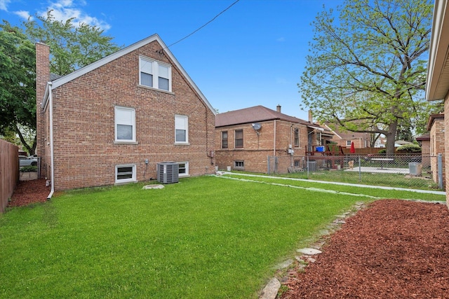 back of house with a chimney, brick siding, and cooling unit