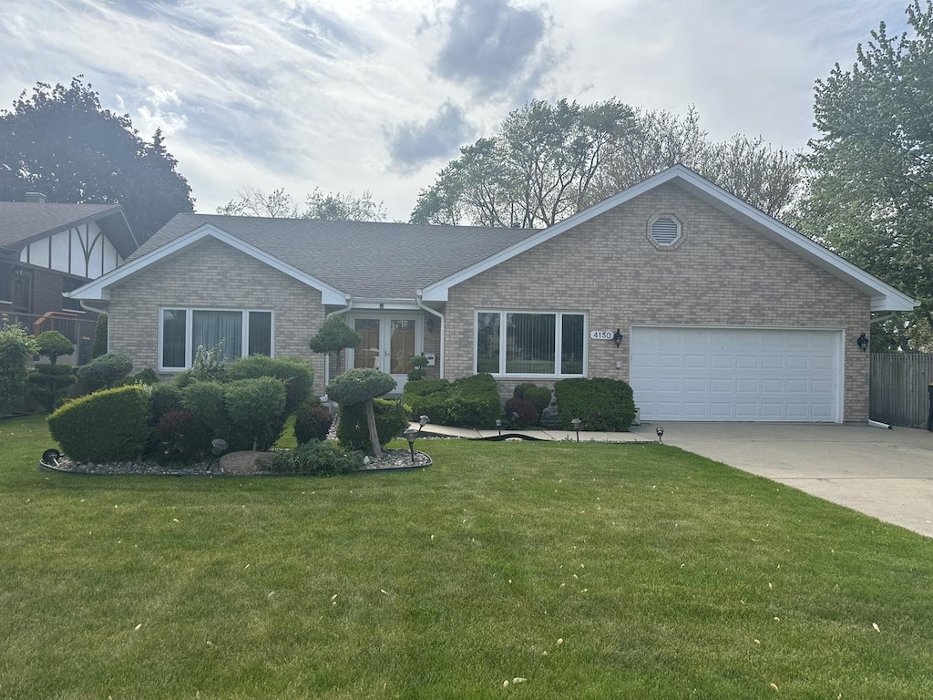 view of front of property with brick siding, concrete driveway, a front yard, and an attached garage