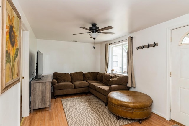 living area featuring light wood-style flooring and a ceiling fan