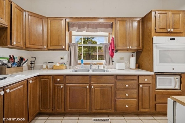 5115 Greenwood Pl, Mccullom Lake, IL 60050 - kitchen with white appliances, a sink, light countertops, light tile patterned flooring, and brown cabinetry