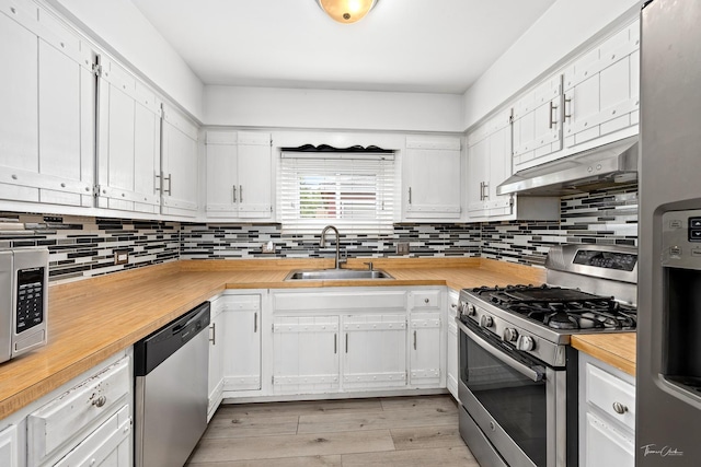 440 Berkshire Ave, Romeoville, IL 60446 - kitchen featuring appliances with stainless steel finishes, a sink, under cabinet range hood, wood counters, and decorative backsplash