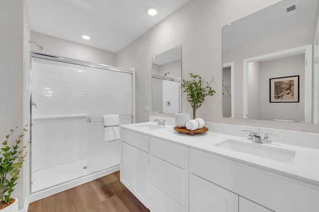 bathroom with a stall shower, wood finished floors, and double vanity