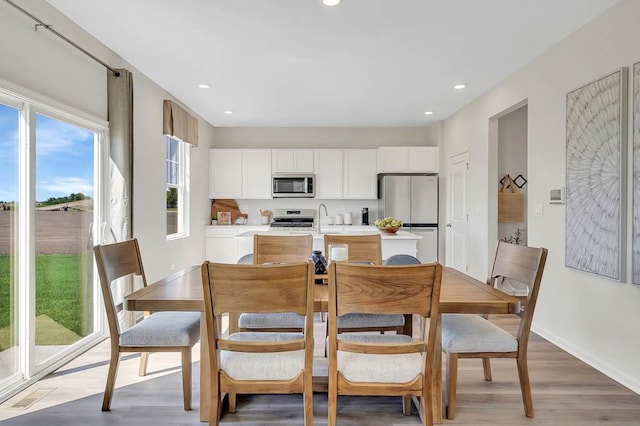 dining space with light wood-type flooring, recessed lighting, and baseboards