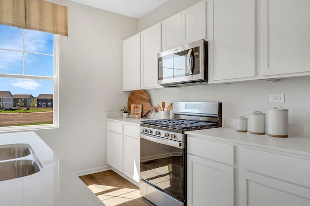 kitchen featuring stainless steel appliances, light wood finished floors, white cabinets, and light countertops