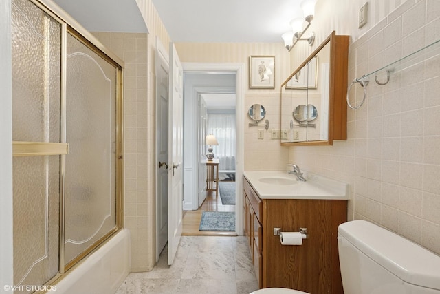 5530 Theobald Rd, Morton Grove, IL 60053 - bathroom featuring vanity, toilet, marble finish flooring, tile walls, and shower / bath combination with glass door