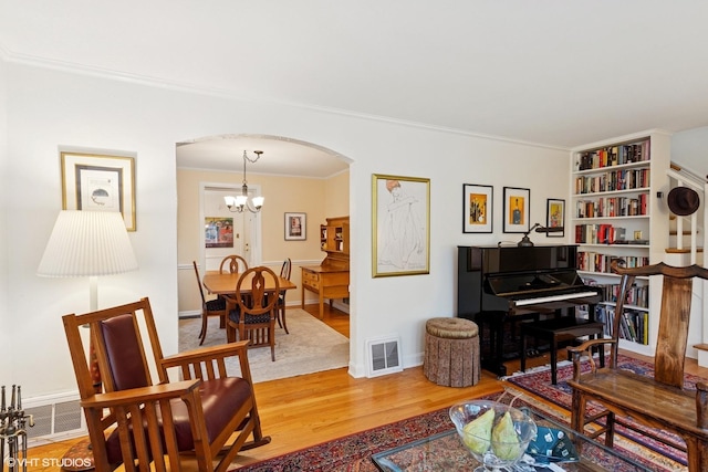 5530 Theobald Rd, Morton Grove, IL 60053 - living room featuring arched walkways, light wood finished floors, ornamental molding, a chandelier, and baseboards