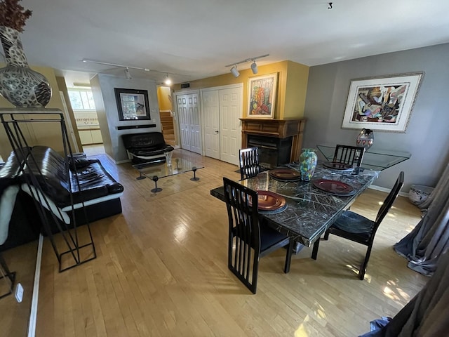 dining area with track lighting, hardwood / wood-style floors, baseboards, and a fireplace