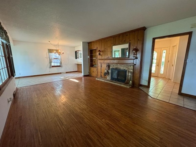 110 Martin Dr, Rock Falls, IL 61071 - unfurnished living room featuring a chandelier, wood finished floors, a glass covered fireplace, wooden walls, and a textured ceiling