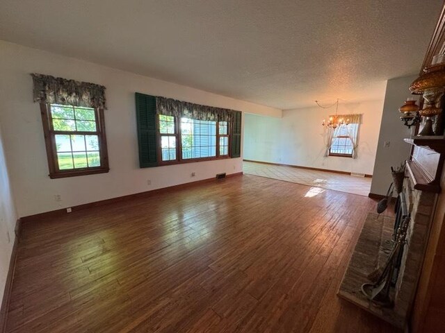 110 Martin Dr, Rock Falls, IL 61071 - unfurnished living room featuring a chandelier, wood finished floors, a textured ceiling, and a fireplace