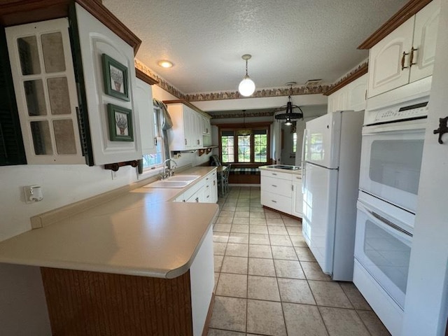 110 Martin Dr, Rock Falls, IL 61071 - kitchen with a peninsula, white appliances, a textured ceiling, light countertops, and white cabinetry