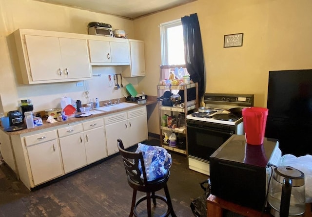 4943 W Monroe St, Chicago, IL 60644 - kitchen with range with electric stovetop, white cabinetry, a sink, light countertops, and dark wood-style floors