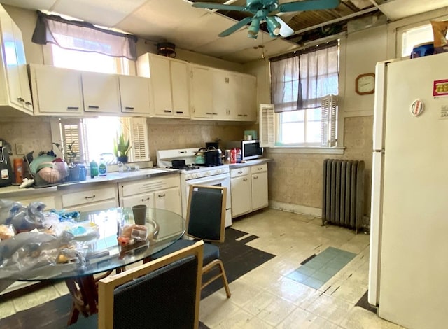 4943 W Monroe St, Chicago, IL 60644 - kitchen featuring radiator heating unit, white appliances, light floors, ceiling fan, and white cabinetry