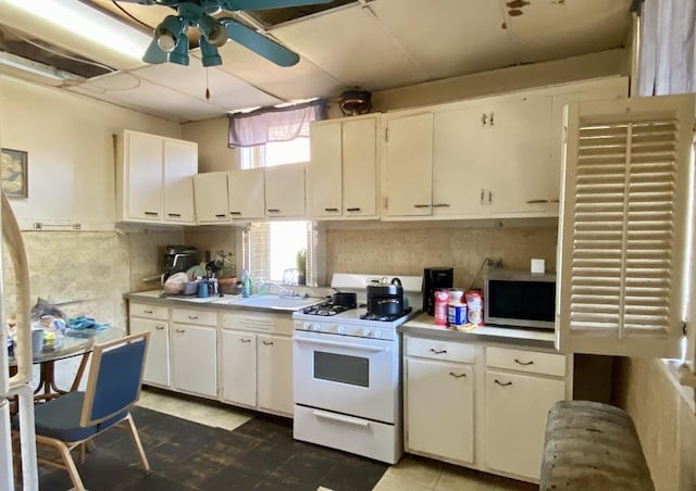 4943 W Monroe St, Chicago, IL 60644 - kitchen featuring gas range gas stove, stainless steel microwave, a ceiling fan, a sink, and white cabinetry