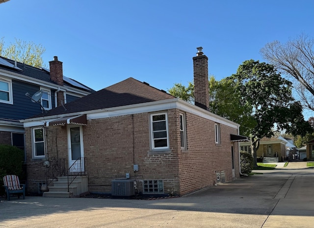 7727 W Palatine Ave, Chicago, IL 60631 - view of property exterior featuring a chimney, brick siding, cooling unit, and entry steps