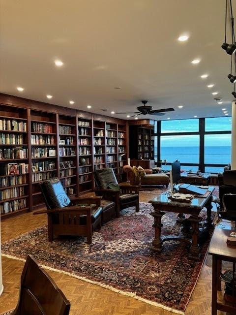 living room featuring bookshelves, a ceiling fan, a wall of windows, and recessed lighting