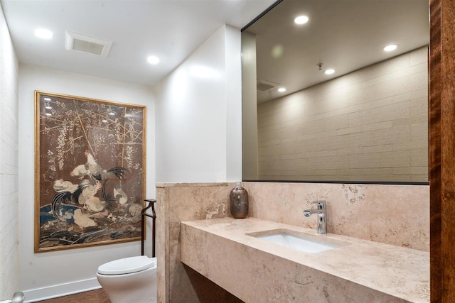 bathroom featuring toilet, recessed lighting, and vanity