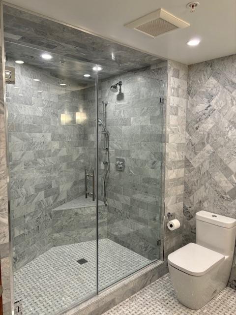 full bath with toilet, a shower stall, and tile walls
