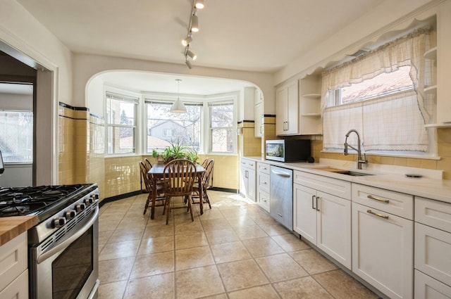 6504 N Artesian Ave, Chicago, IL 60645 - kitchen featuring appliances with stainless steel finishes, a sink, arched walkways, backsplash, and open shelves