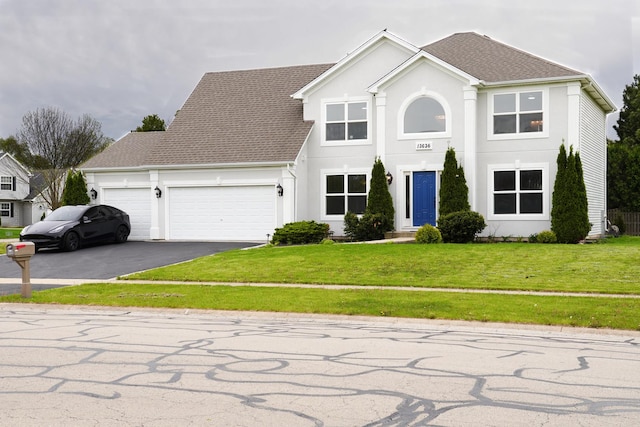 13636 Savanna Dr, Plainfield, IL 60544 - colonial-style house featuring asphalt driveway, an attached garage, a front yard, roof with shingles, and stucco siding