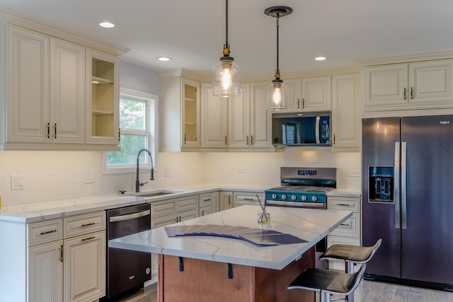 13636 Savanna Dr, Plainfield, IL 60544 - kitchen featuring stainless steel appliances, a sink, a center island, light stone countertops, and a kitchen breakfast bar