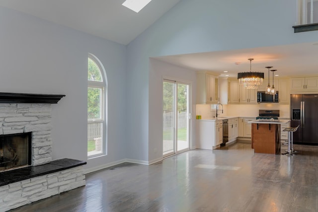 13636 Savanna Dr, Plainfield, IL 60544 - unfurnished living room with a sink, a chandelier, dark wood-type flooring, a stone fireplace, and high vaulted ceiling