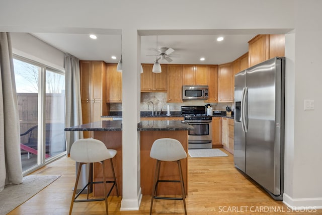 647 Glacier Trl, Roselle, IL 60172 - kitchen with stainless steel appliances, a kitchen island, light wood-type flooring, a ceiling fan, and a kitchen bar