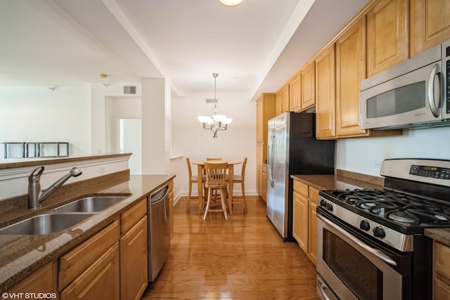 2700 Summit Dr Unit 307, Glenview, IL 60025 - kitchen featuring appliances with stainless steel finishes, a sink, a chandelier, light wood-style floors, and dark stone counters