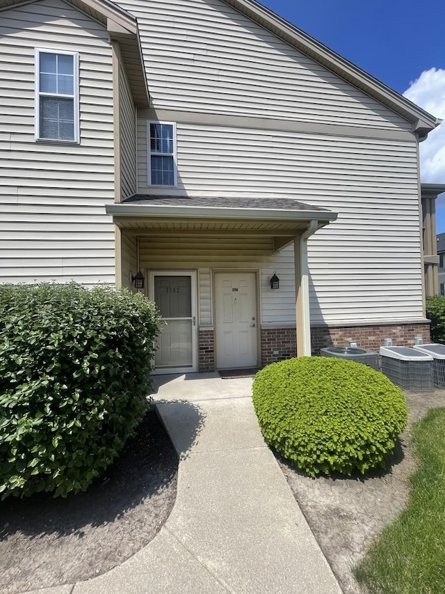 entrance to property with central AC unit and brick siding
