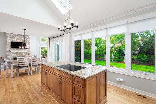 3211 Treyburn Rd, Naperville, IL 60564 - kitchen with black electric cooktop, brown cabinetry, light wood finished floors, light stone counters, and pendant lighting