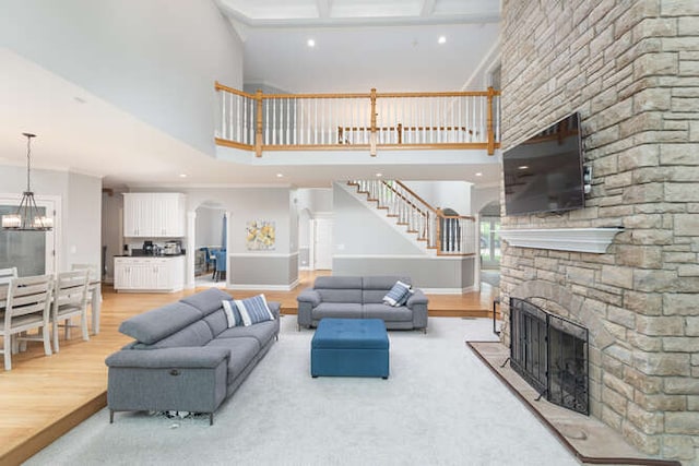 3211 Treyburn Rd, Naperville, IL 60564 - living room with a stone fireplace, a high ceiling, stairs, wood finished floors, and a chandelier