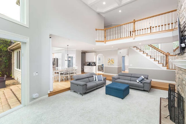 3211 Treyburn Rd, Naperville, IL 60564 - carpeted living area with a high ceiling, a stone fireplace, healthy amount of natural light, stairway, and baseboards