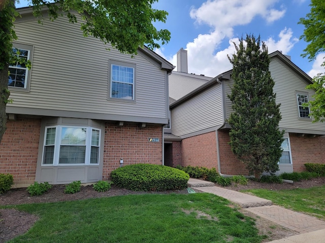 1744 Eastwood Ct Unit 9, Schaumburg, IL 60195 - view of front of house featuring brick siding, a front yard, and a chimney