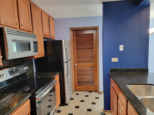 1744 Eastwood Ct Unit 9, Schaumburg, IL 60195 - kitchen with stainless steel range with electric stovetop, white microwave, light floors, dark stone countertops, and brown cabinetry