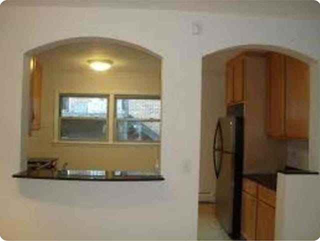 1238 W Pratt Blvd Unit 1A, Chicago, IL 60626 - kitchen featuring freestanding refrigerator, arched walkways, brown cabinetry, and dark countertops