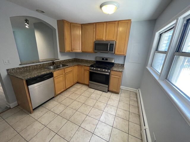 1238 W Pratt Blvd Unit 1A, Chicago, IL 60626 - kitchen featuring appliances with stainless steel finishes, baseboard heating, light tile patterned floors, arched walkways, and dark stone countertops