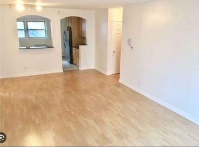 1238 W Pratt Blvd Unit 1A, Chicago, IL 60626 - unfurnished room featuring arched walkways, wood finished floors, and baseboards