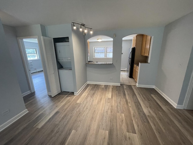 1238 W Pratt Blvd Unit 1A, Chicago, IL 60626 - unfurnished living room with stacked washer / dryer, plenty of natural light, a baseboard radiator, and arched walkways