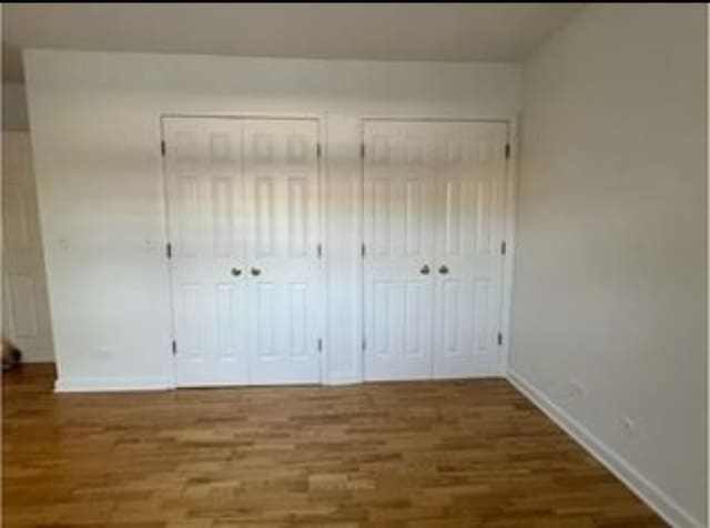 1238 W Pratt Blvd Unit 1A, Chicago, IL 60626 - unfurnished bedroom featuring multiple closets, wood finished floors, and baseboards