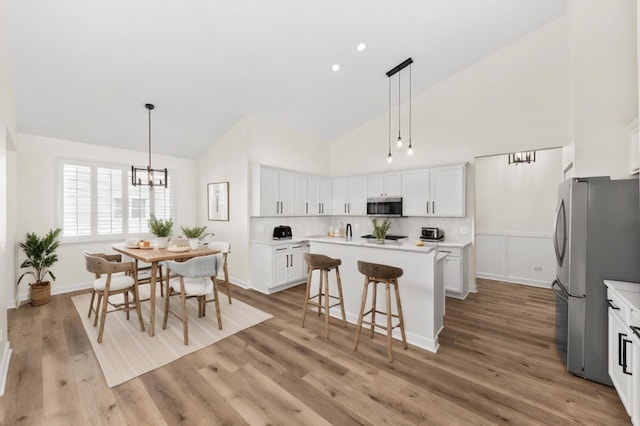 1468 W Grand Haven Rd, Romeoville, IL 60446 - kitchen with stainless steel appliances, high vaulted ceiling, a kitchen island, a chandelier, and white cabinets