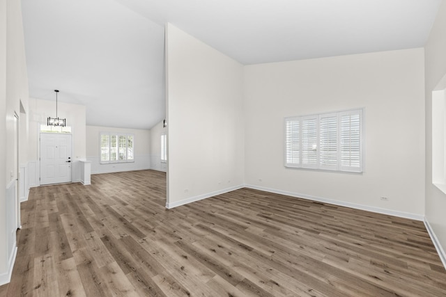 1468 W Grand Haven Rd, Romeoville, IL 60446 - unfurnished living room featuring light wood-type flooring, baseboards, a chandelier, and vaulted ceiling