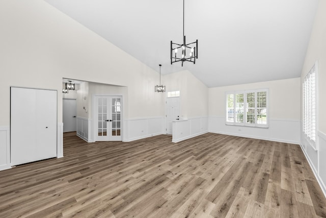 1468 W Grand Haven Rd, Romeoville, IL 60446 - unfurnished living room with a chandelier, high vaulted ceiling, wood finished floors, a wainscoted wall, and french doors